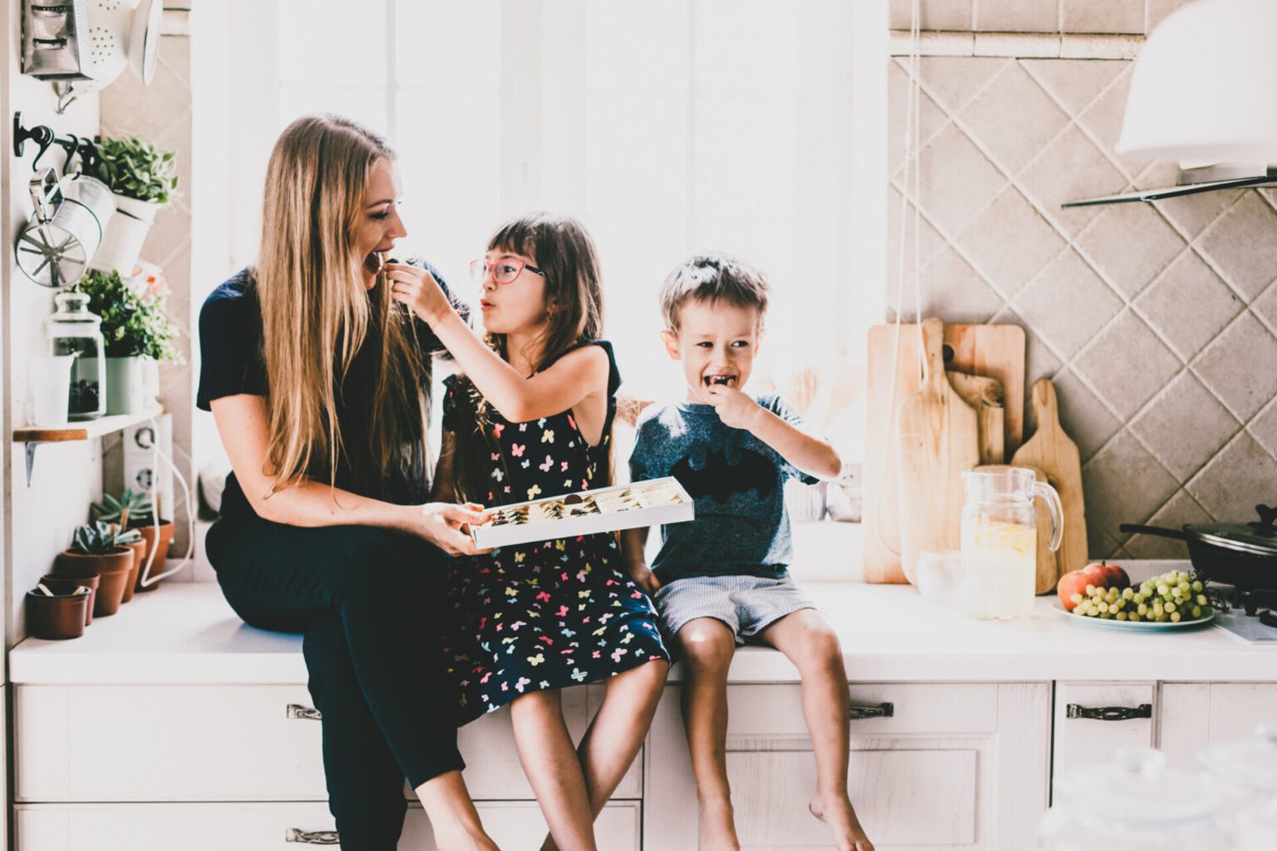 A mom sits next to her kids sharing a snack