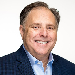 a man wearing a suit and tie smiling at the camera