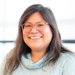 a woman wearing glasses and smiling at the camera